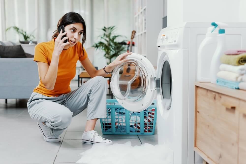 Mujer llamando a reparador para saber como arreglar la lavadora